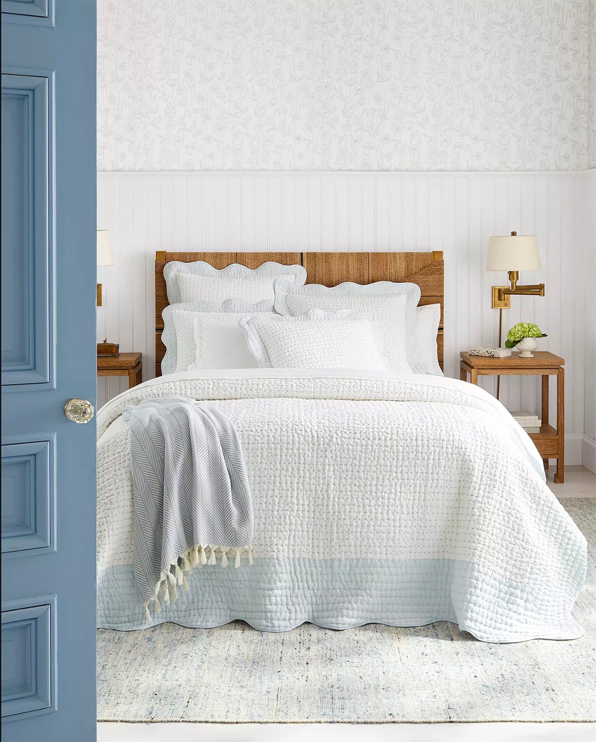 white bedroom with rattan bed with a white and blue quilt