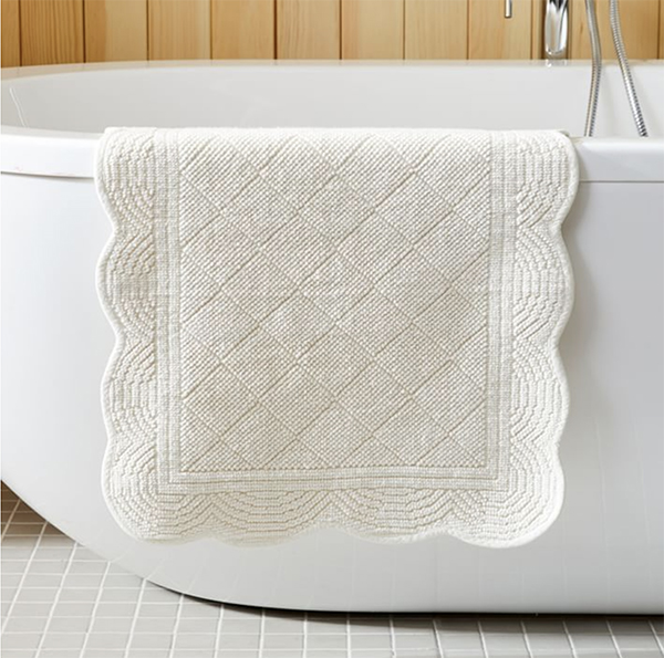 a white scalloped edge bath mat