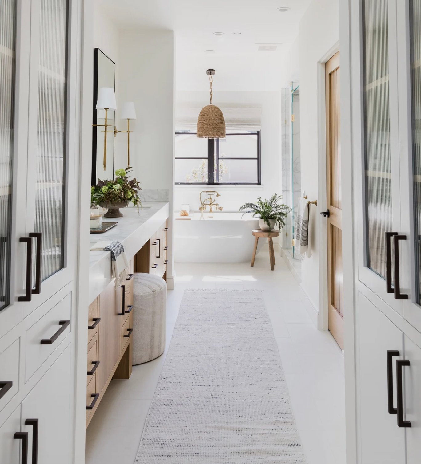 large bathroom with black hardware and a tub with a brass faucet