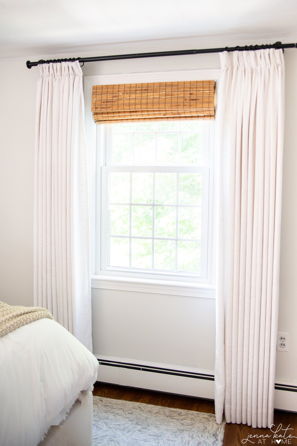 light colored curtains with a bamboo shade and black curtain rod