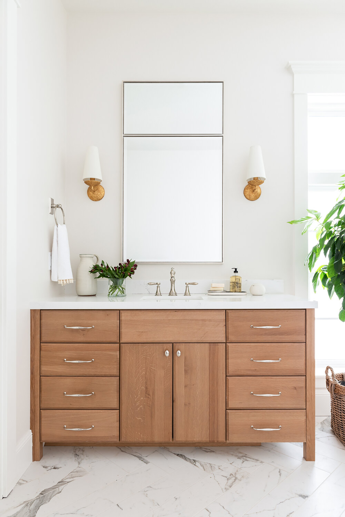 wood vanity with nickel faucet and mirror and brass sconces
