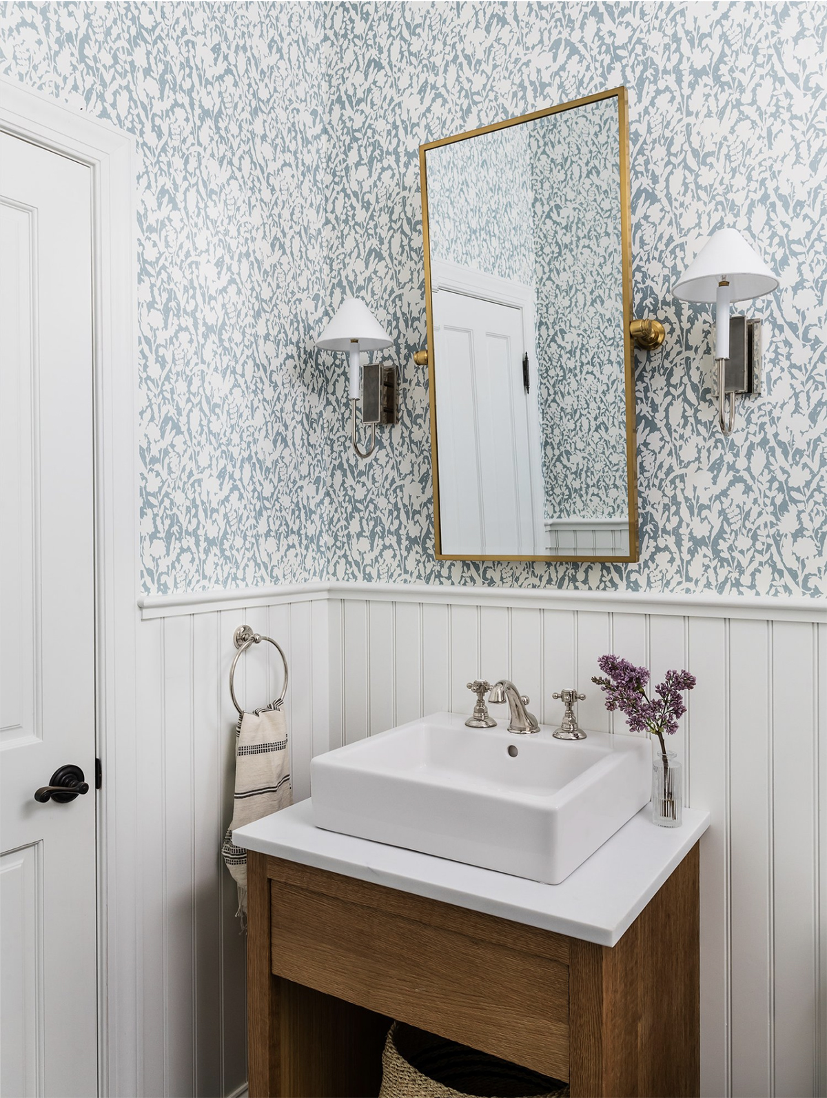 small bathroom with blue wallpaper and mixed metals
