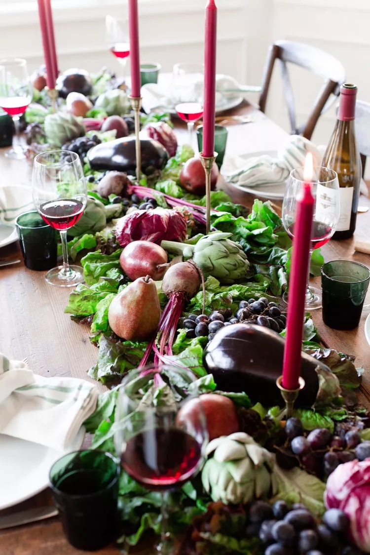 Stunning green and wine colored Thanksgiving table with produce and candlesticks