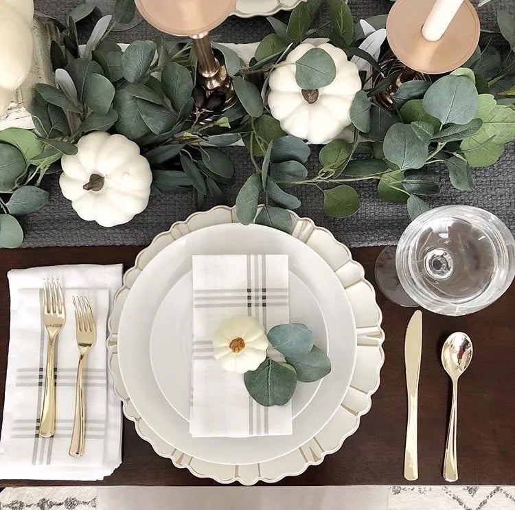 Elegant table decor with eucalyptus branches, white mini pumpkins and neutral plates
