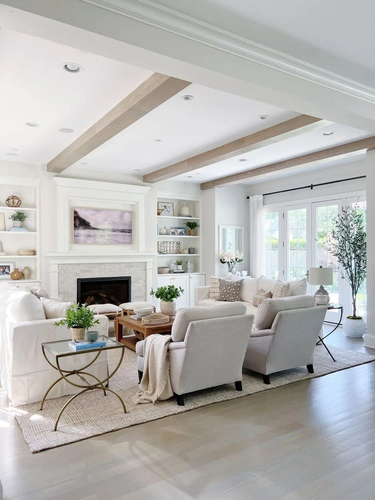 living room with classic gray walls, wood beams on the ceiling and light colored couches and chairs