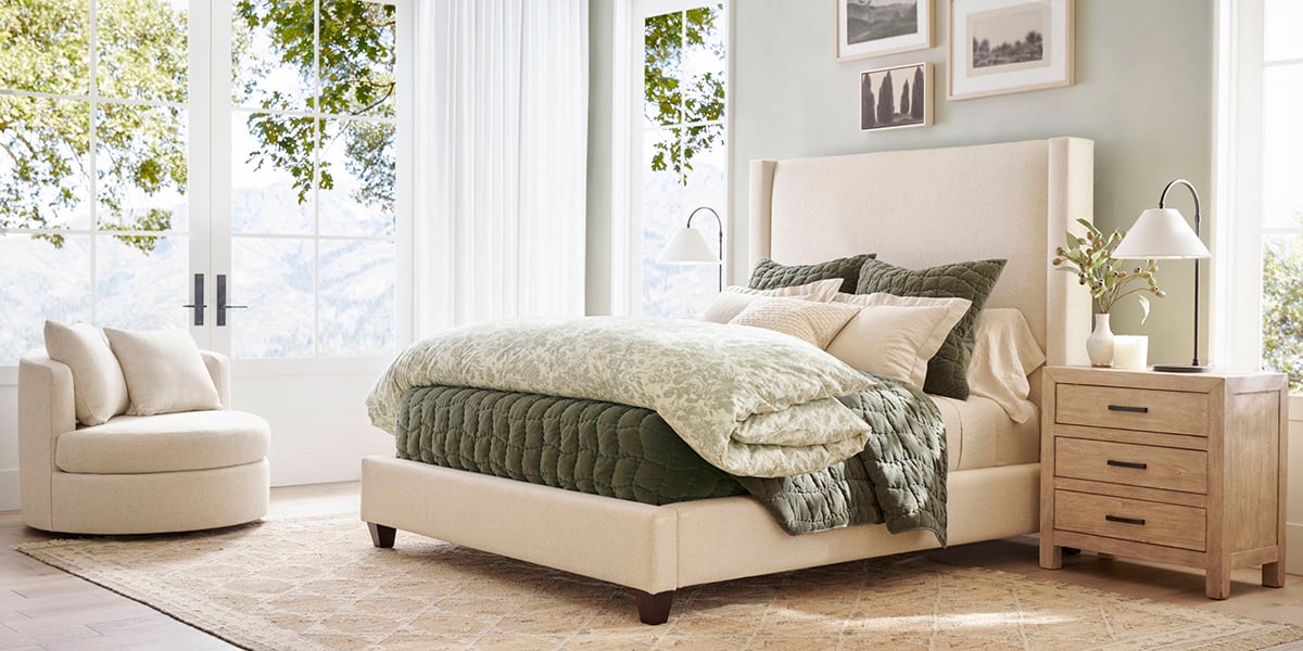 bedroom with a upholstered bed with green bedding layers.