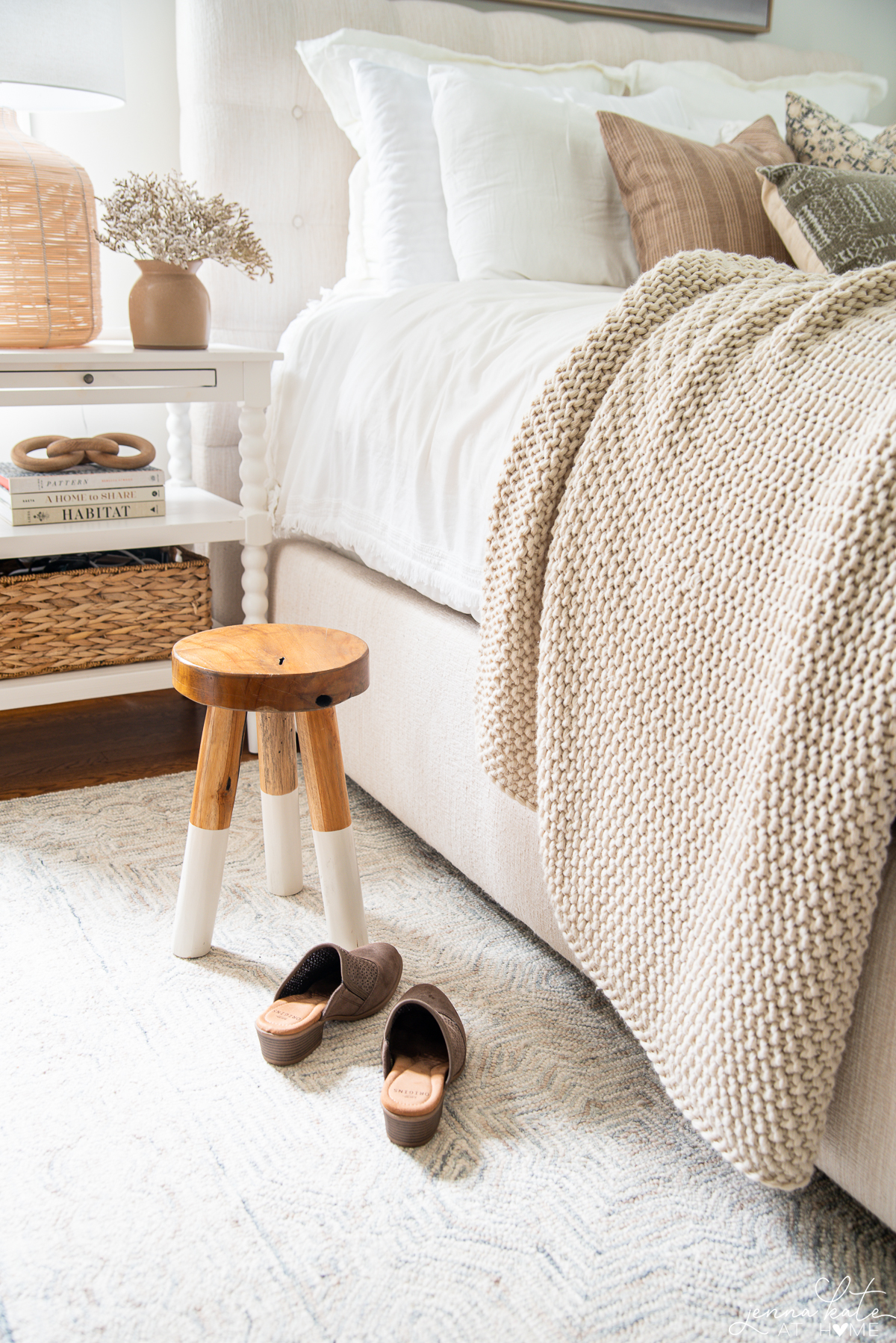 bed with a wooden stool and women's shoes on the rug next to it