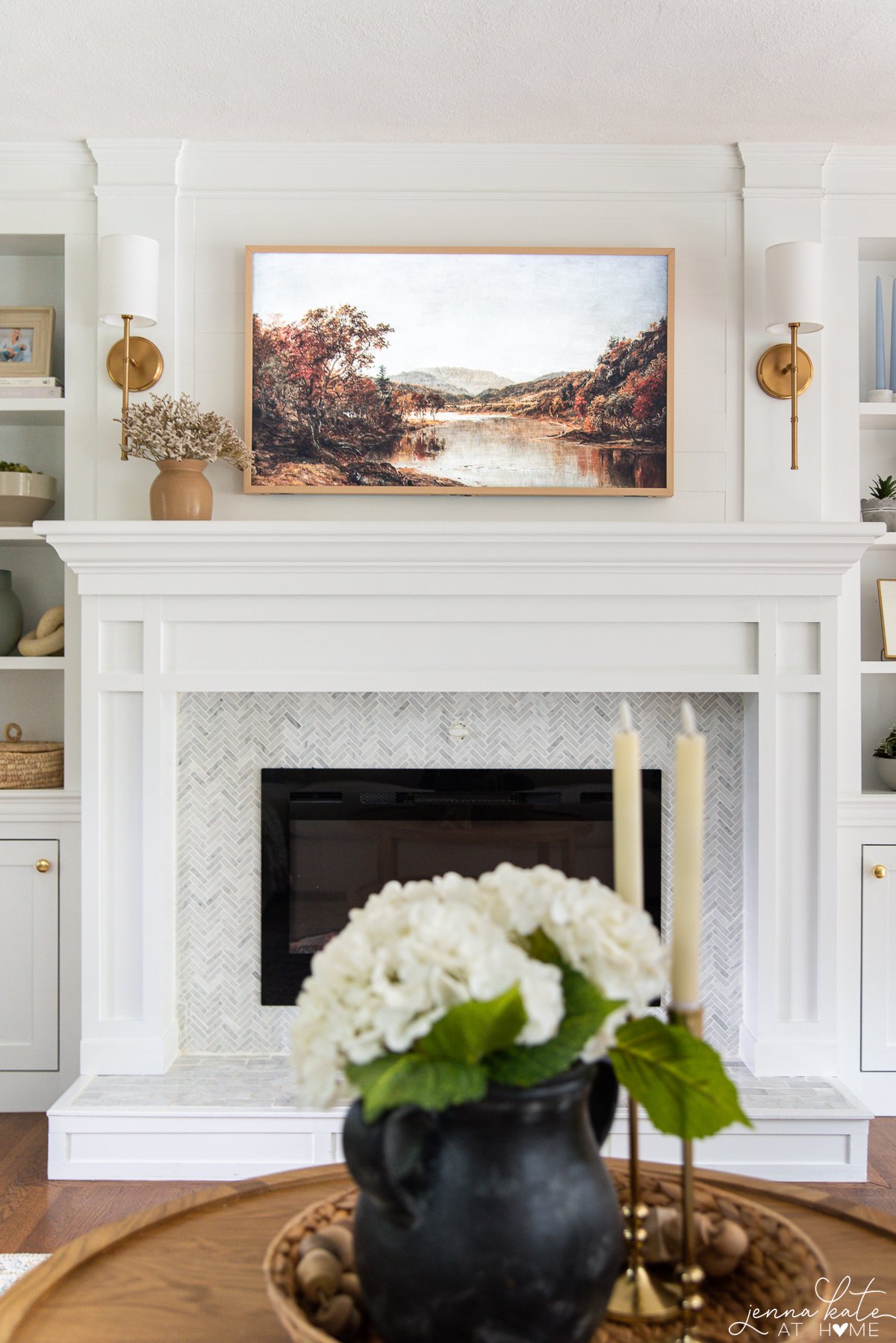 frame TV over a fireplace mantel with fall artwork