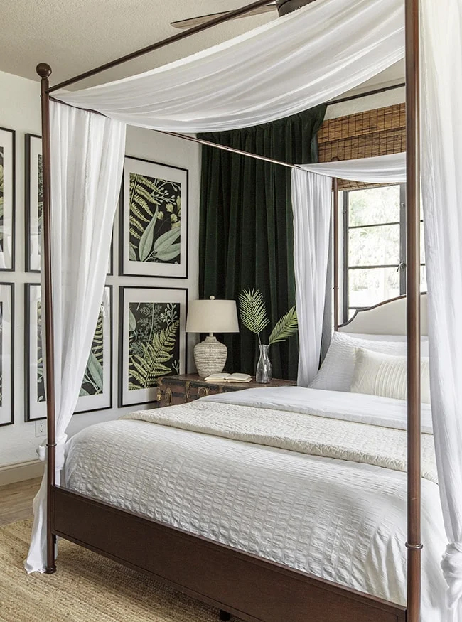 bedroom with four poster bed, leaf artwork and dark green curtains