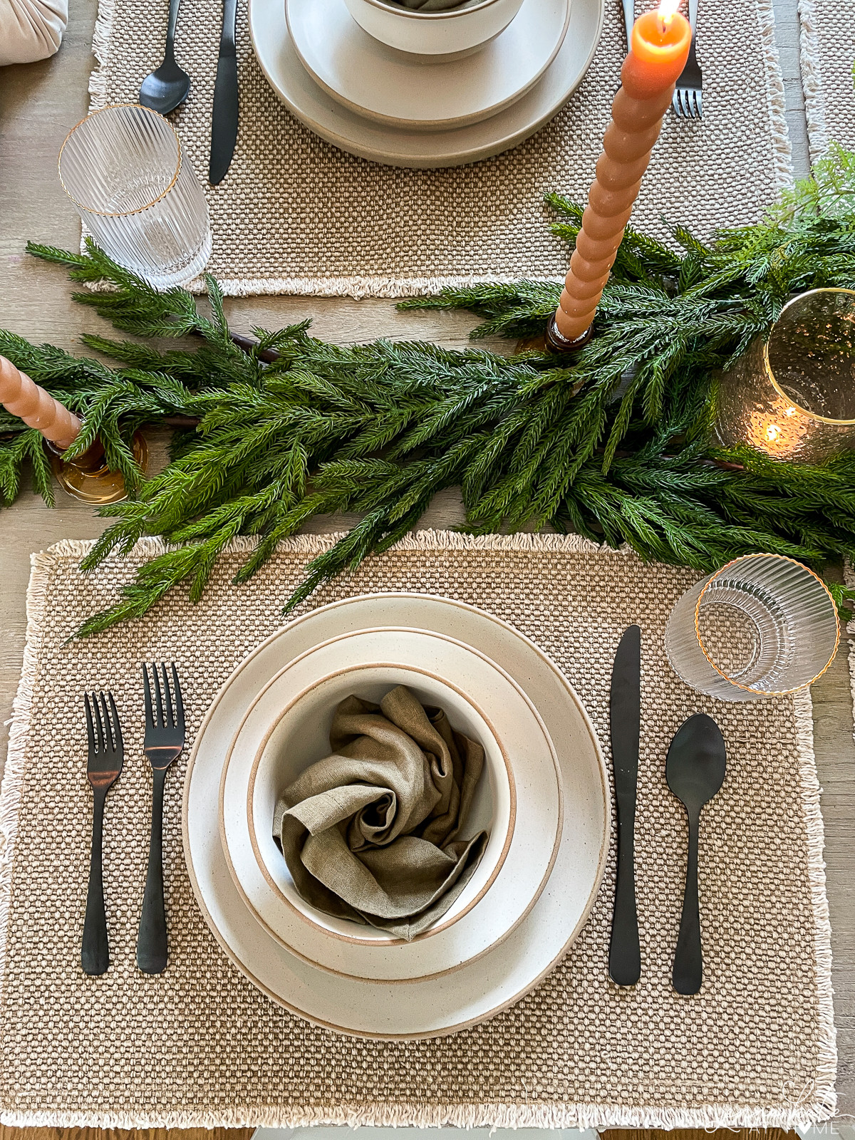 table setting with garland down the center and neutral color placemats and plates