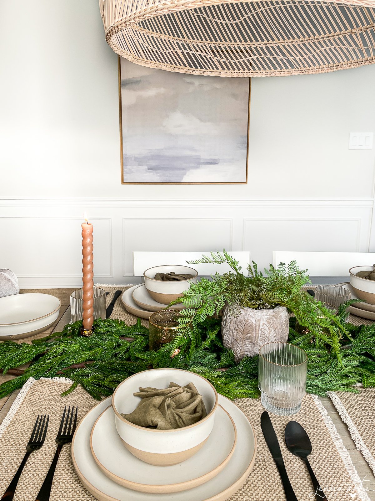 holiday table setting with greenery garland and neutral dishes