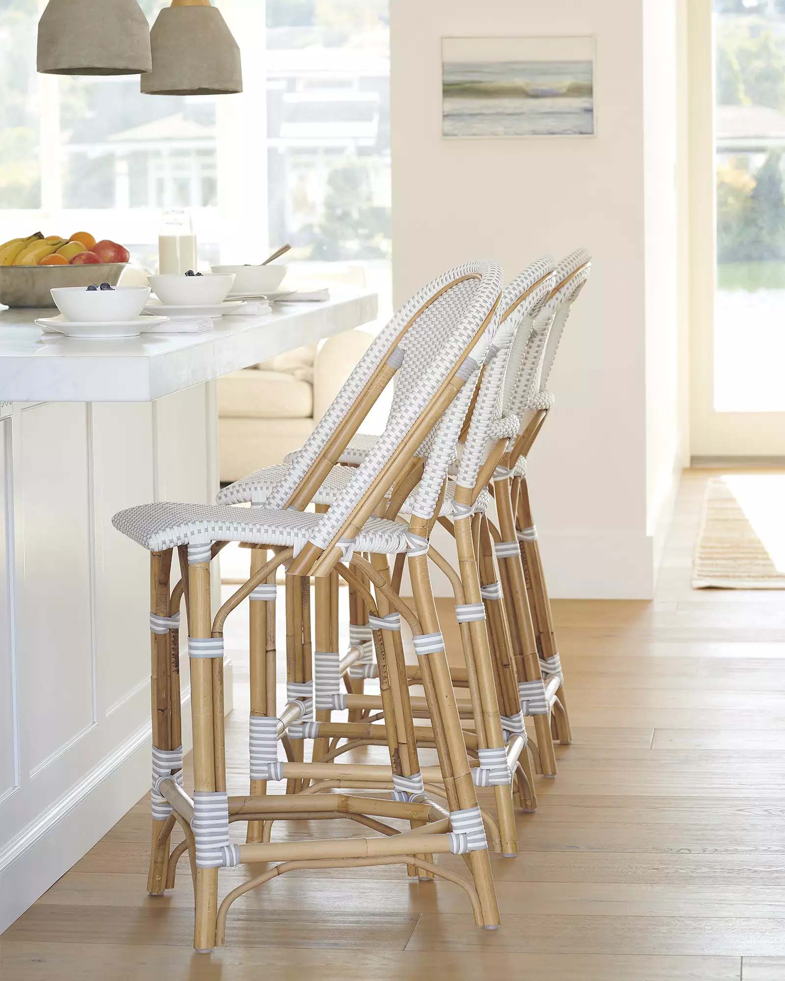 three white and wood island chairs at a white kitchen island.
