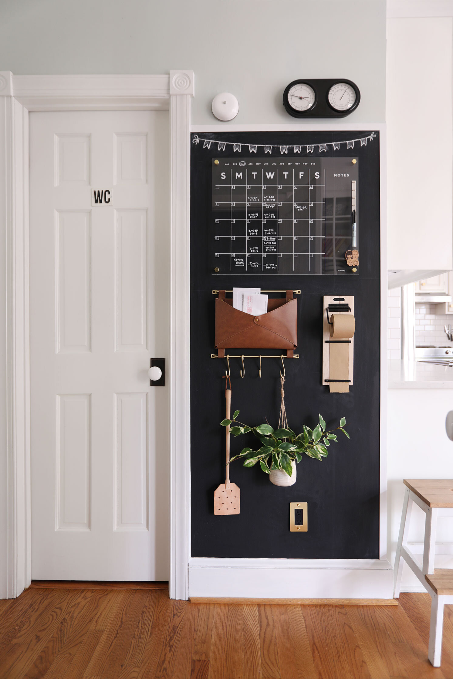 modern family command center with a black painted wall, clear dry erase board calendar, and neutral colored decor.