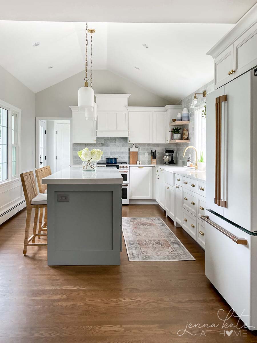 east and west exposure kitchen with blue gray island, white cabinets and soft warm gray walls