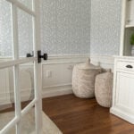 room with warm wood floors, white wainscoting and blue floral wallpaper
