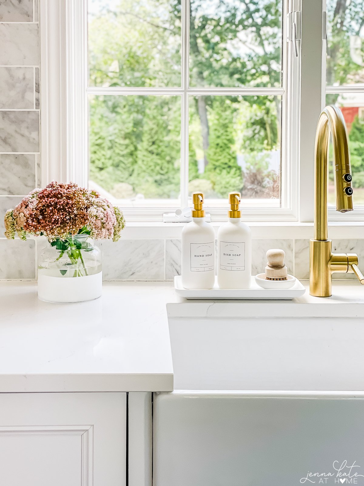 small vase filled with sedum next to a sink with a brass faucet