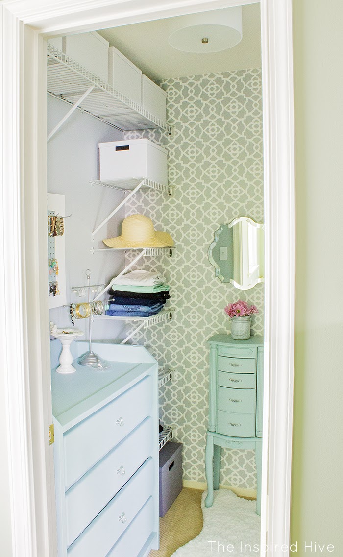 Walk in closet with a wallpapered accent wall.