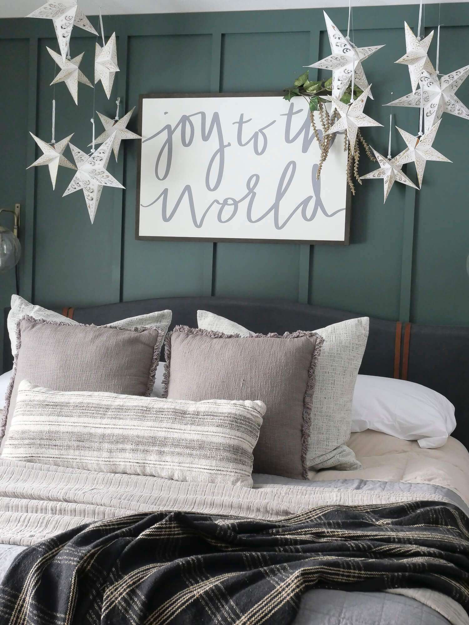 A piece of wall art hanging over a bed reading "Joy to the World"