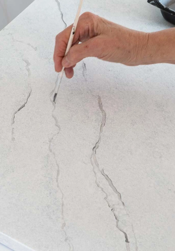 Person drawing veining on a DIY faux carrara marble countertop
