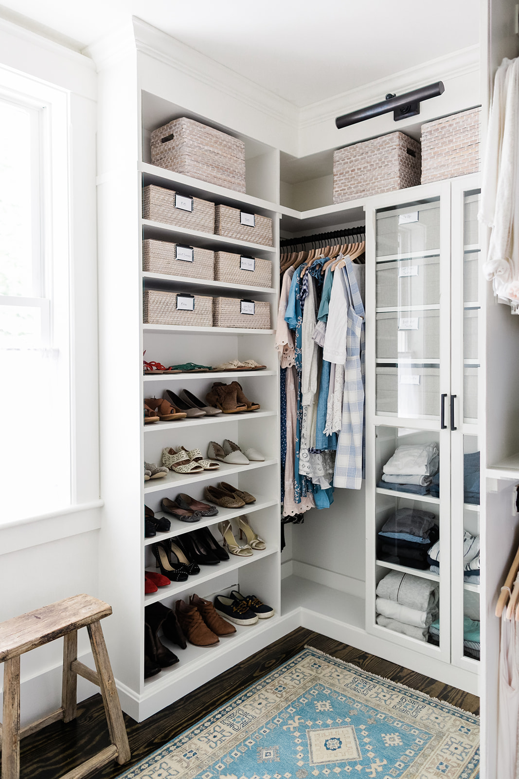 Master bedroom closet with baskets and bins labeled with what is inside of each.