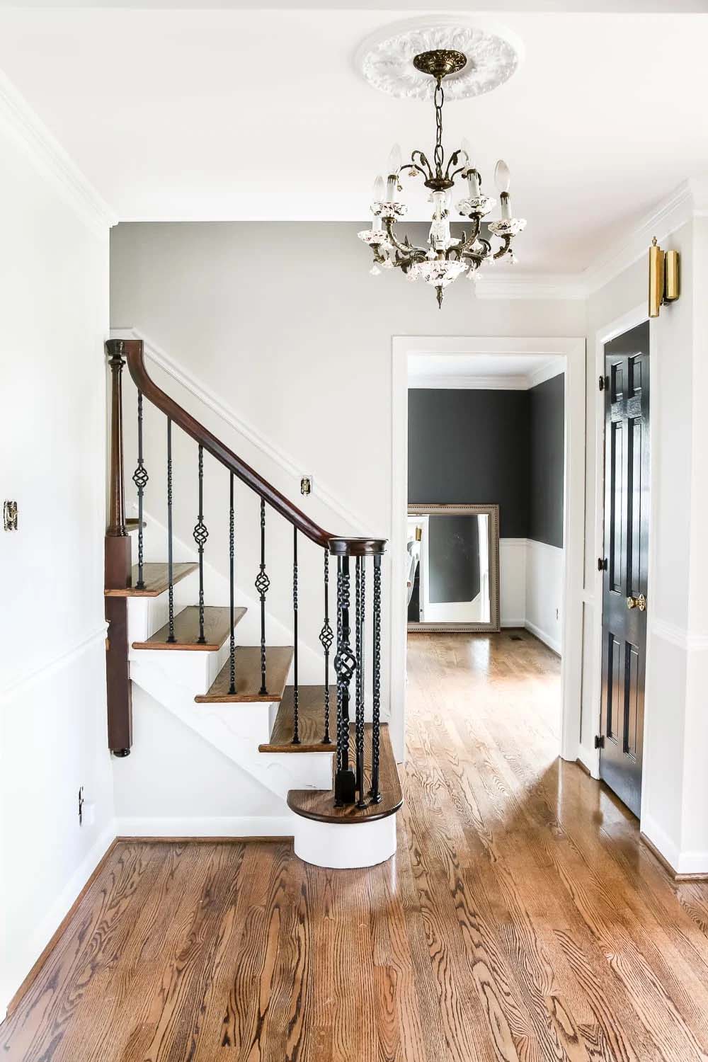 An entryway with a large chandelier, staircase, and hall painted with benjamin moore classic gray