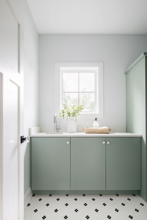 Bathroom cabinets painted sage green with white walls.