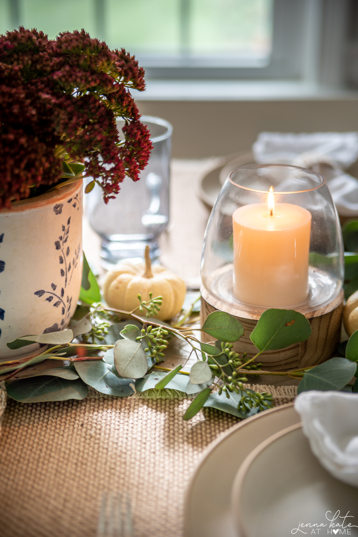 lit candle next to a vase of sedum