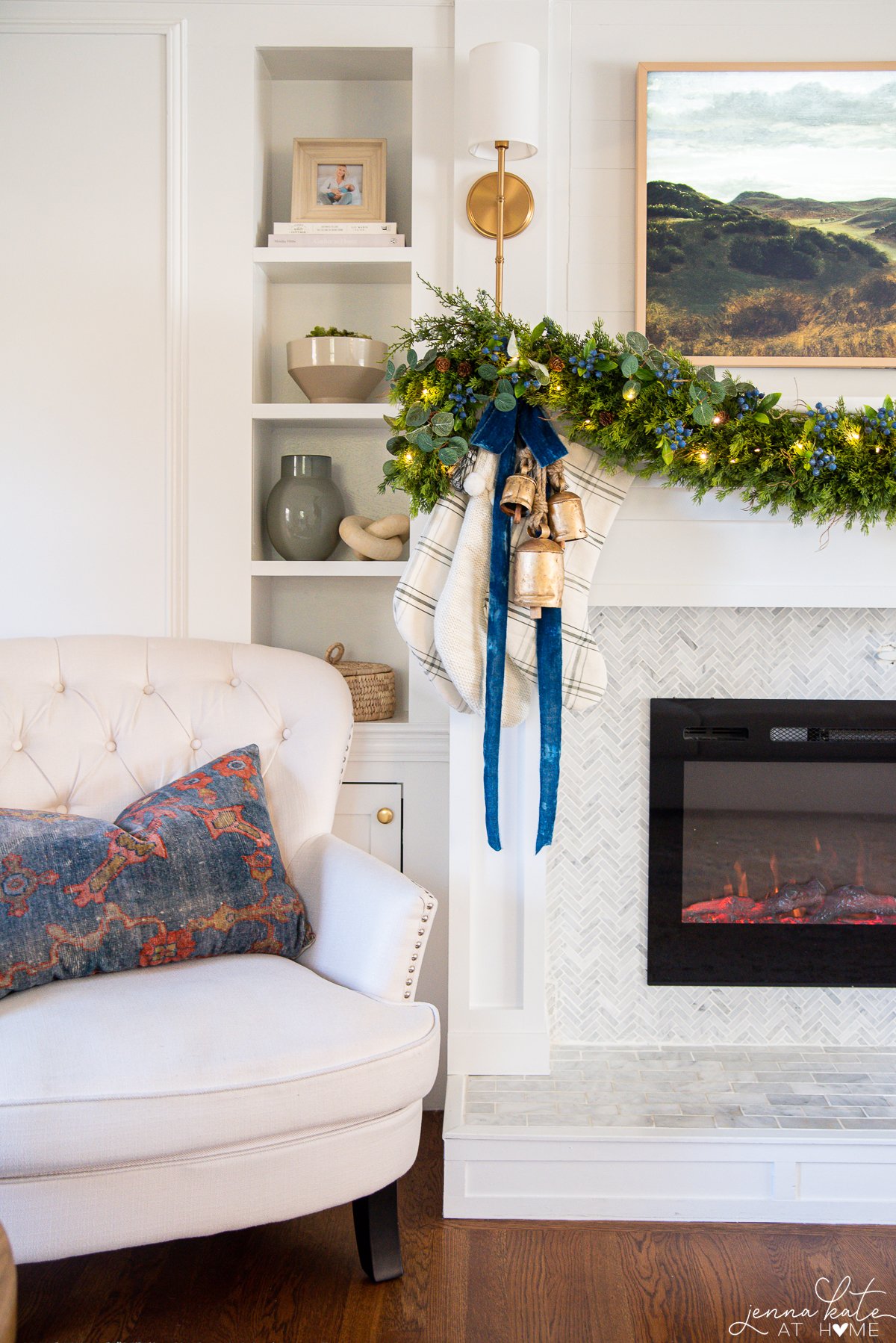 Three stockings hanging off the mantel with gold bells and blue ribbon for Christmas