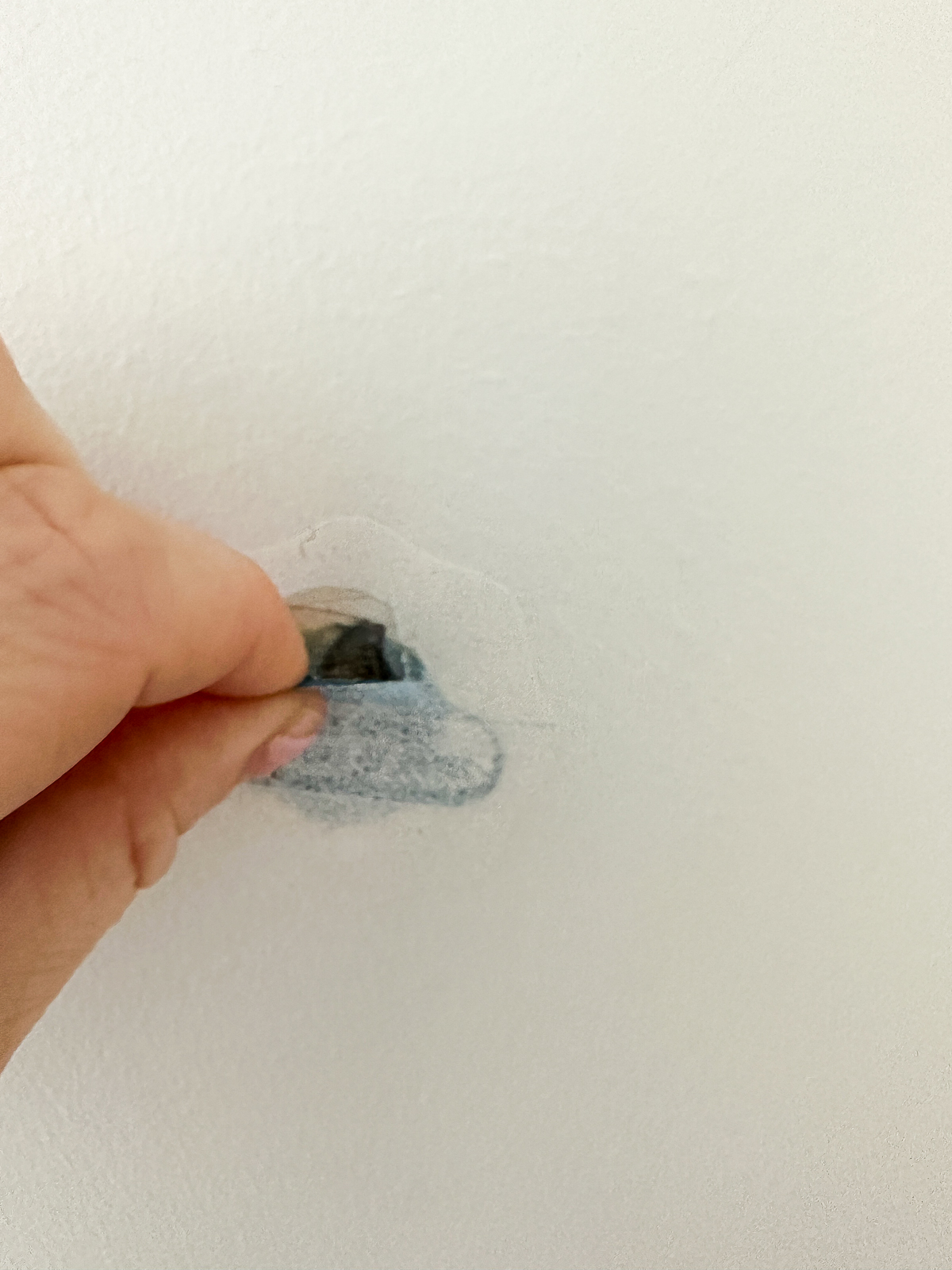 pulling the tab from the patch off the wall