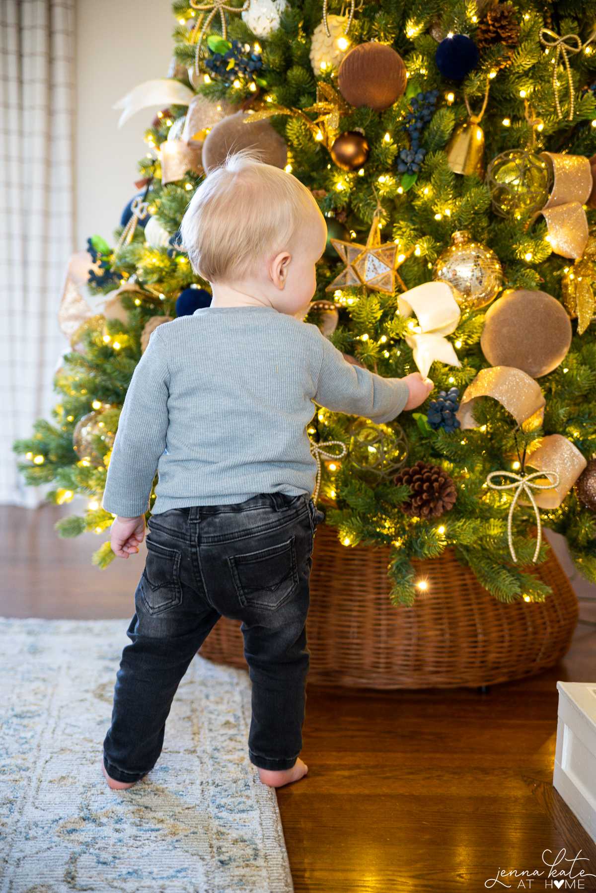 Toddler boy looking at ribbon on the Christmas tree
