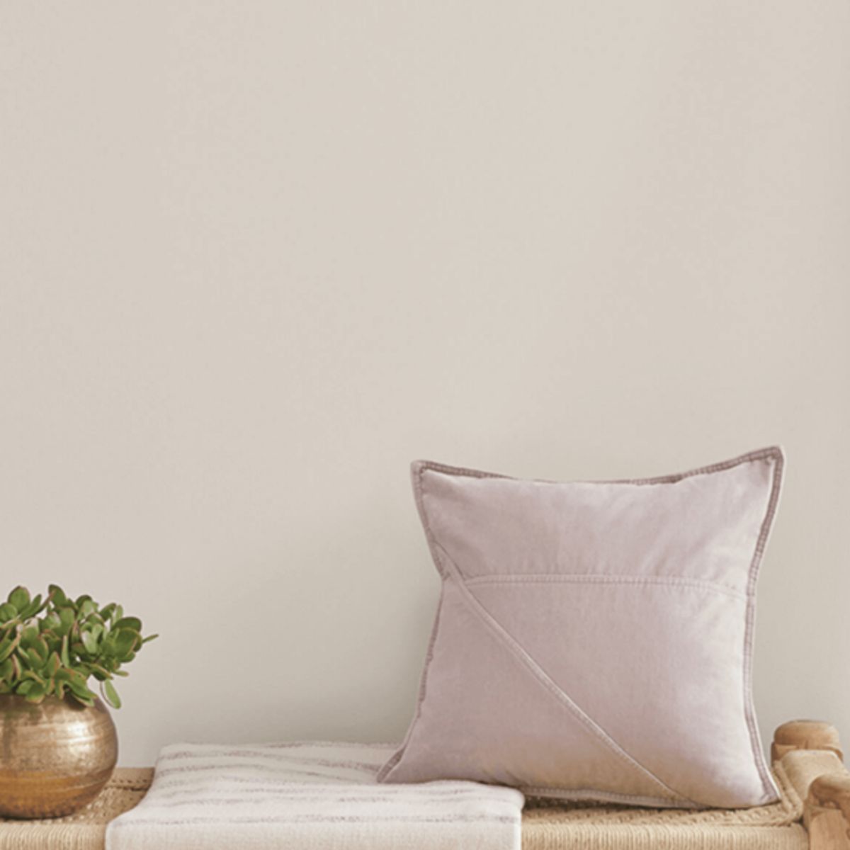 Popular gray painted walls above a bench with a pillow and faux plant on it.