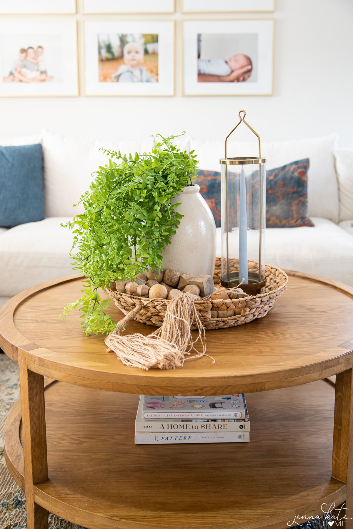 round coffee table with an overflowing green plant, decorative wooden beads and a brass tapered candle holder.