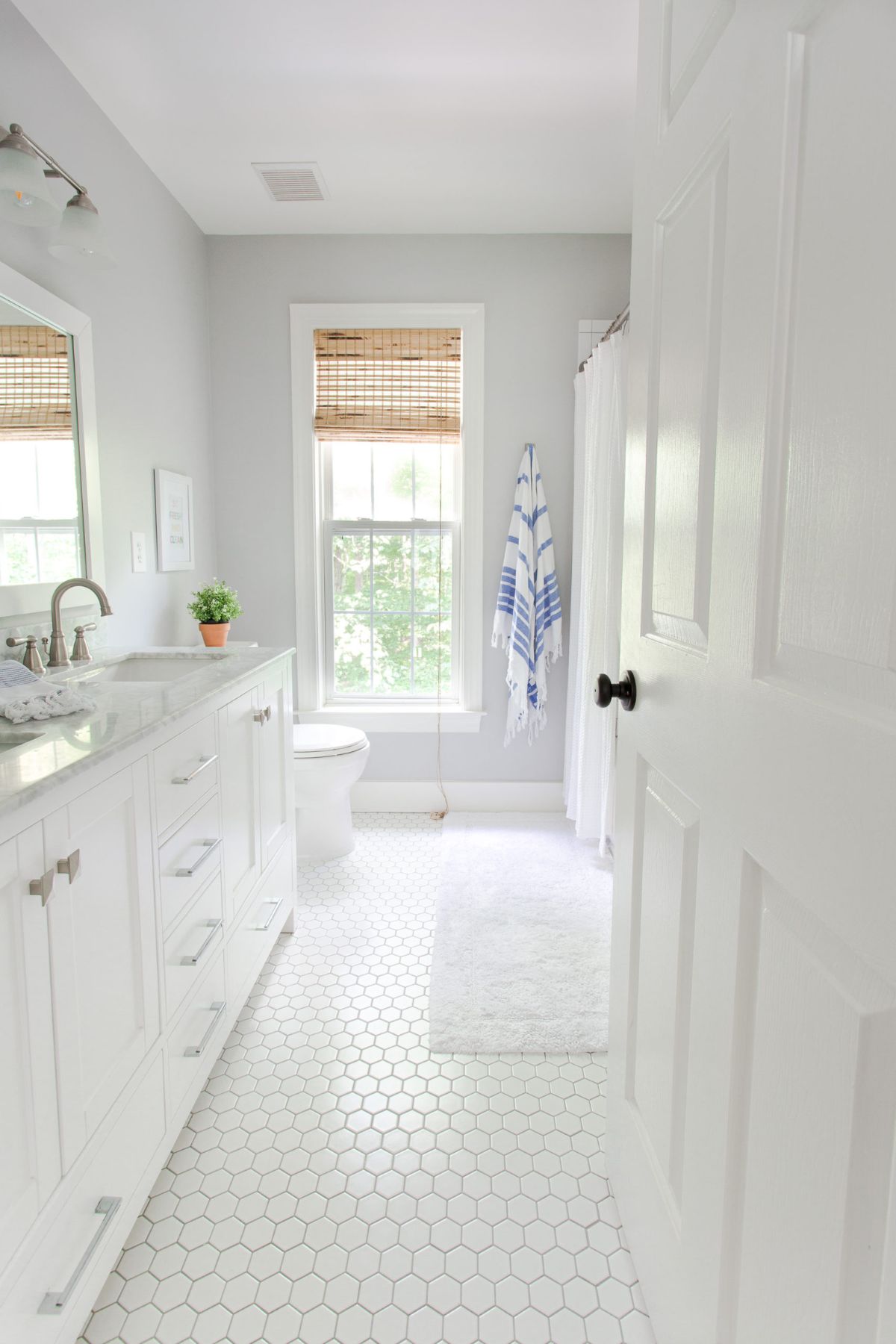 A very clean looking bathroom with a large window and white fixtures.
