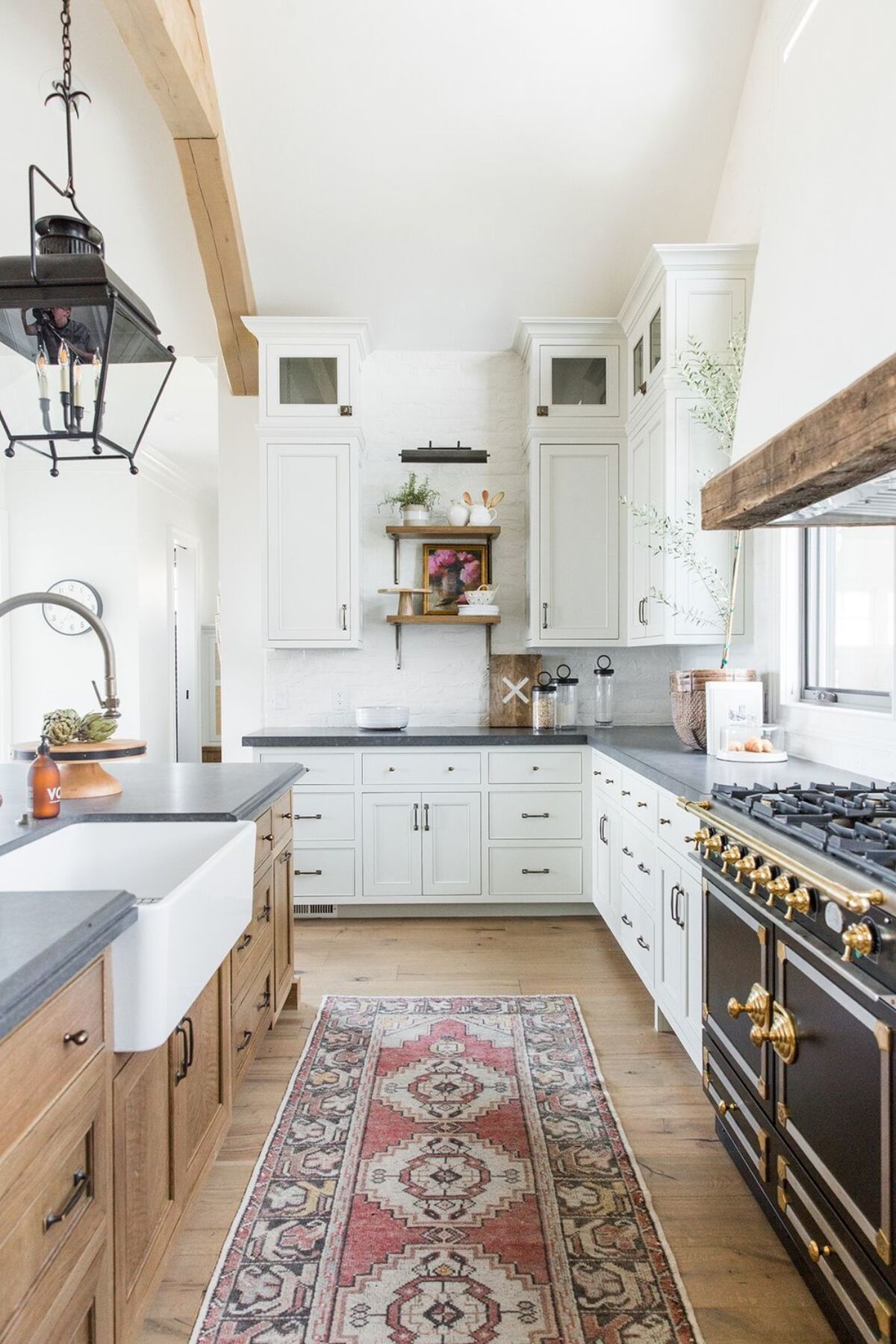 A modern farmhouse kitchen with white cabinets on one side of the kitchen with natural wood cabinets on the kitchen island.