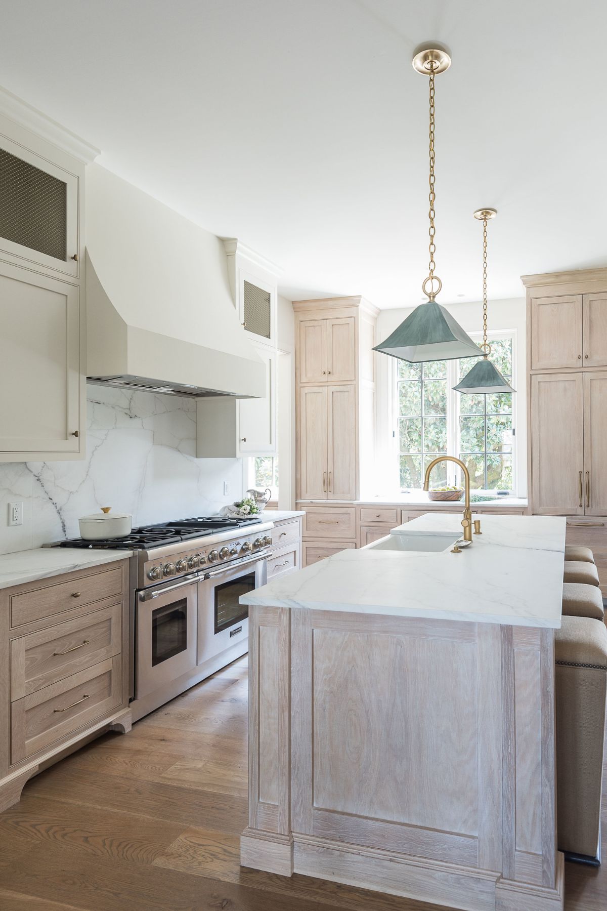 White Oak Cabinets with white countertops and gold hardware in an open concept kitchen.