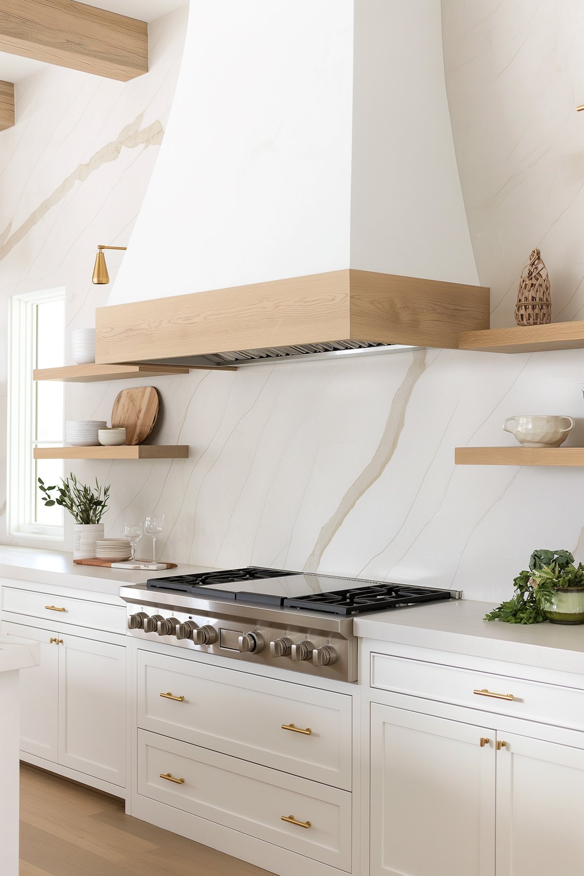 Large white plaster hood with a wood band, a slab marble backsplash and white cabinets.