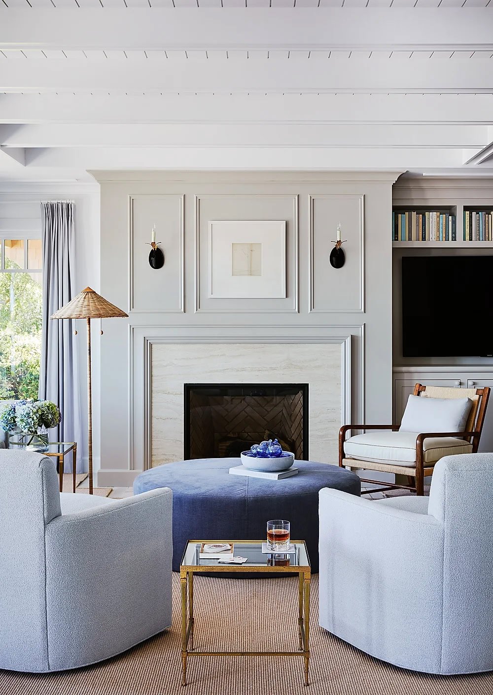 blue arm chairs and upholstered ottoman in front of a fireplace.