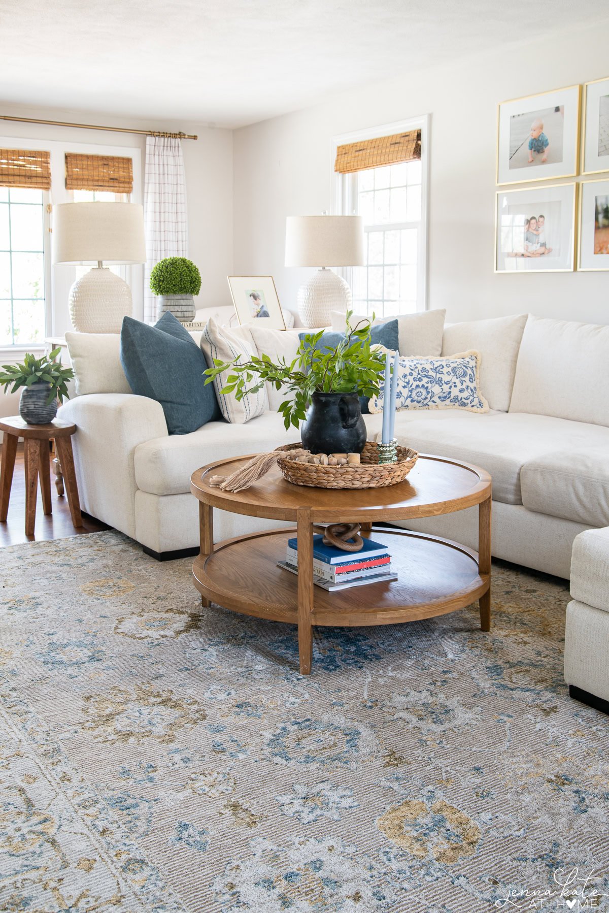 white couch with a round wooden coffee table with a vase of greenery.