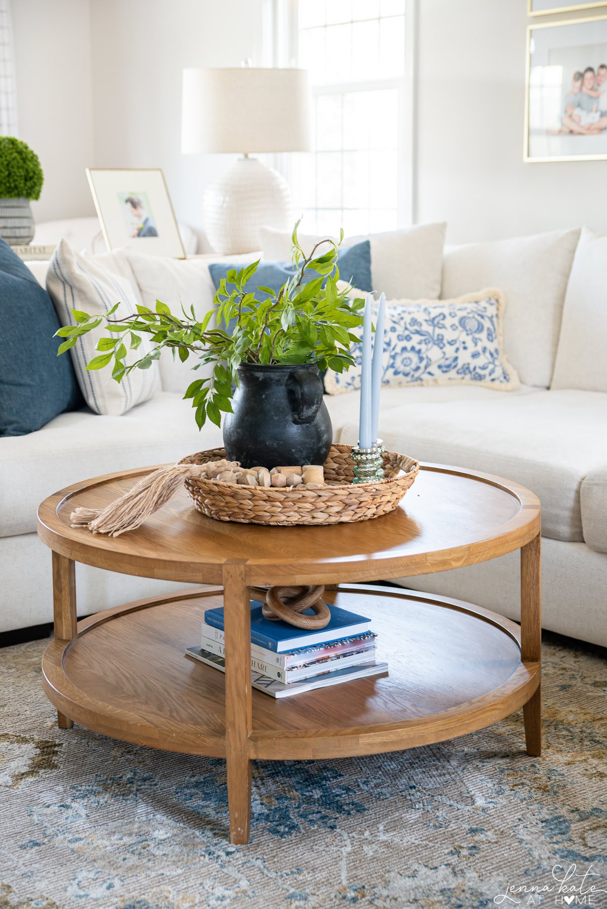 close up of round wooden coffee table with a vase of greenery.
