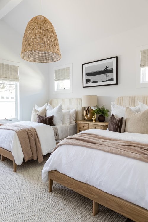 bedroom with two beds, natural tones and a woven bell pendant light.