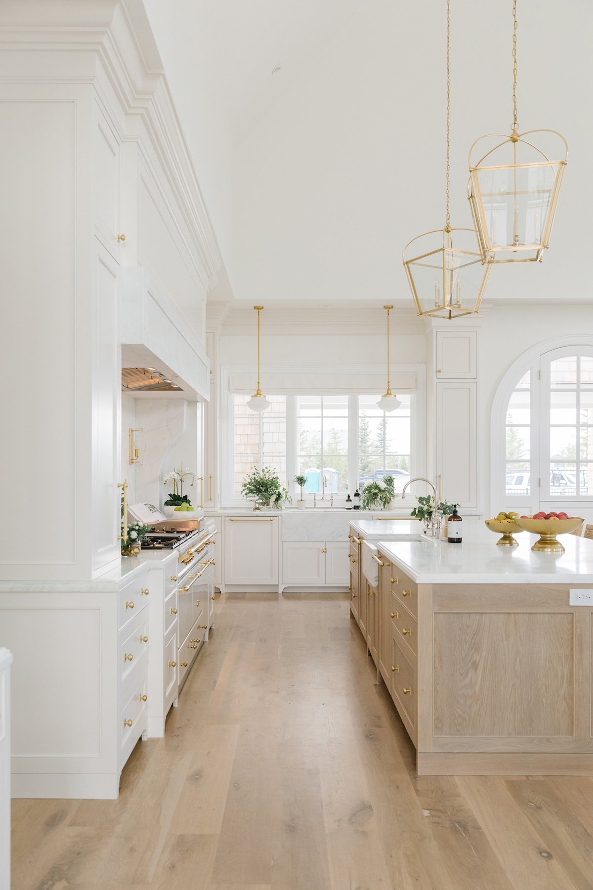 large kitchen with white cabinets, oak island and white countertops. All the fixtures are polished brass.