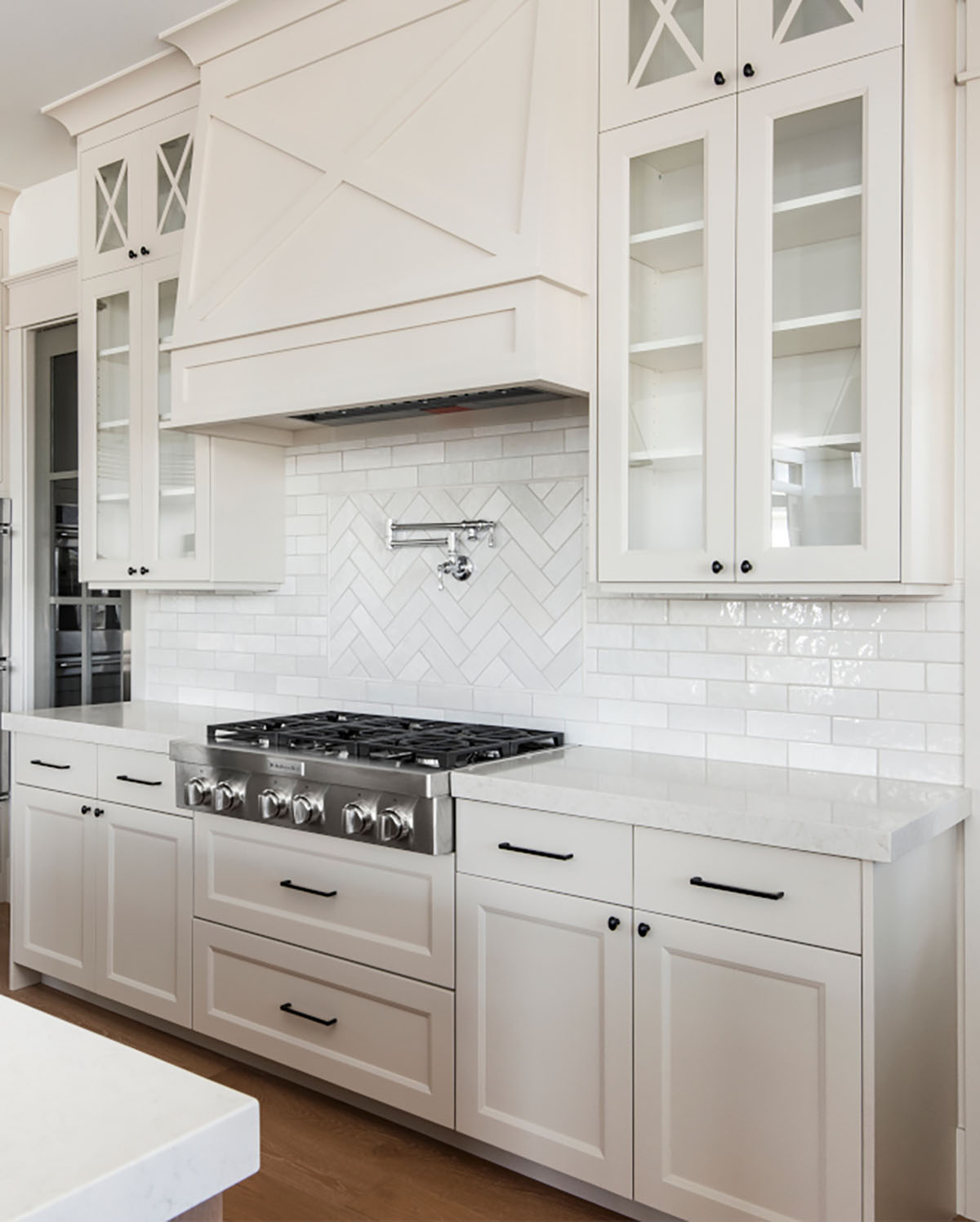 Benjamin Moore Bolboa Mist kitchen cabinets with black hardware, light wood floors, and white backsplash