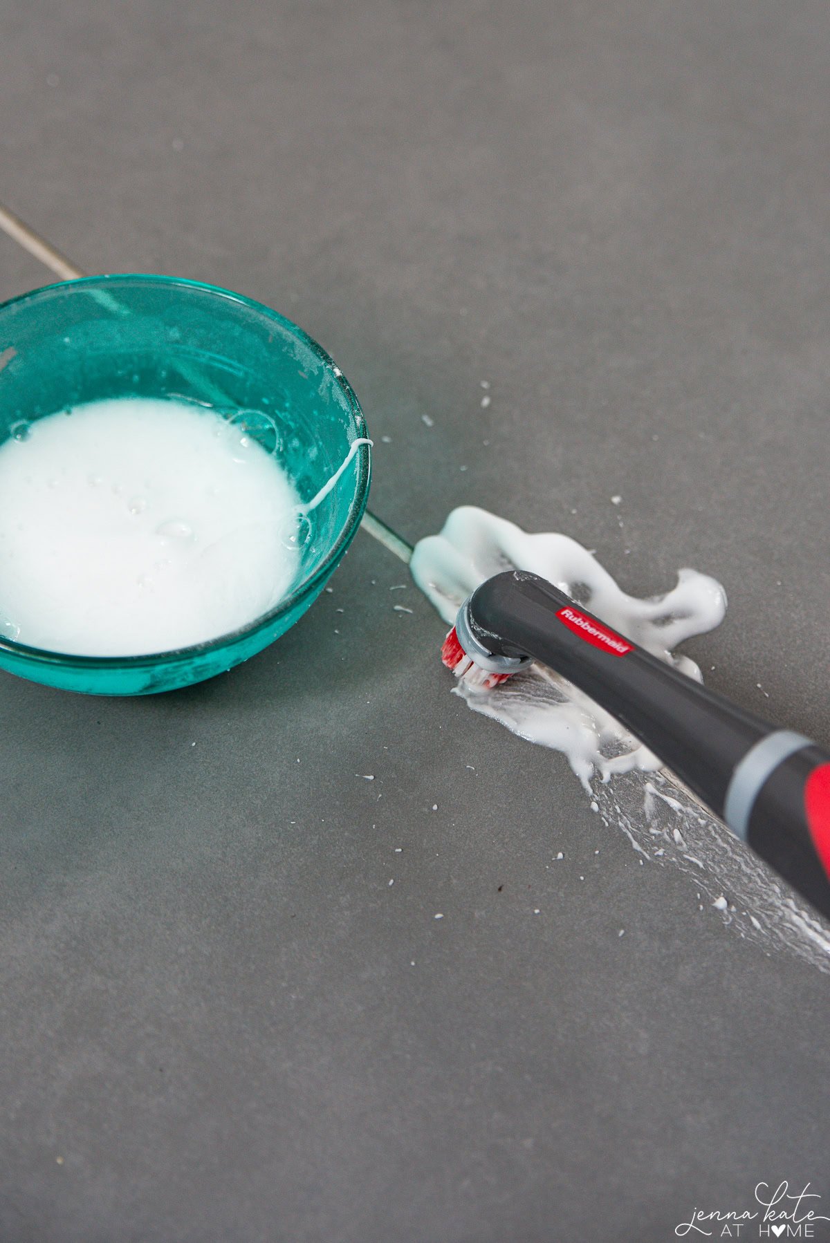 cleaning grout with an electric brush and a bowl of baking soda mixture.