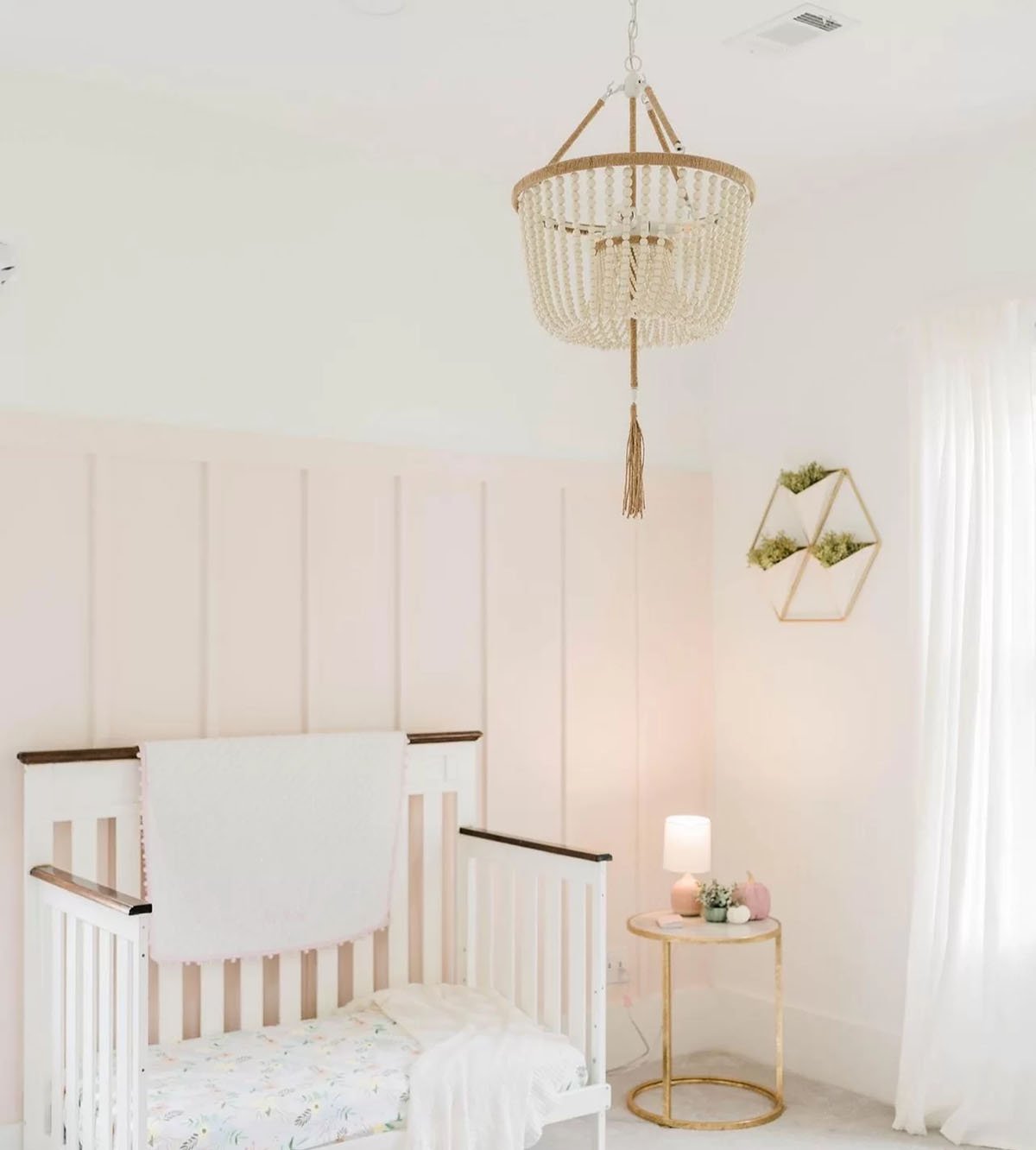 Sherwin Williams Intimate White as an accent wall in a nursery with warm white and gold accents.