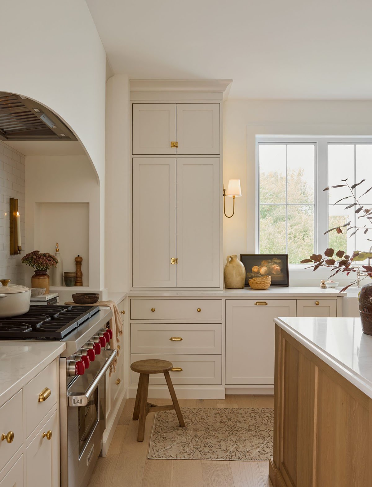 Benjamin Moore Pale Oak on kitchen cabinets with creamy white walls and gold hardware.