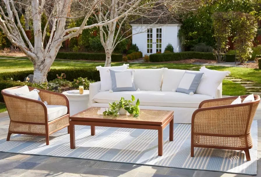 white outdoor couch and two cane armchairs on a patio.