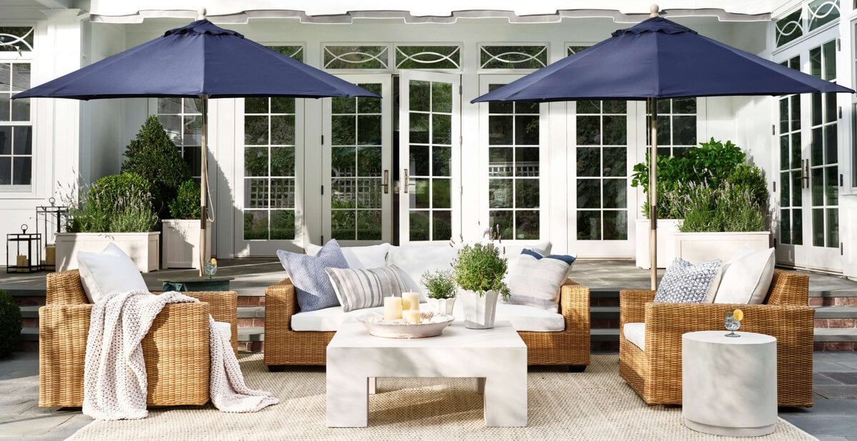 rattan dining set on a patio with two navy patio umbrellas.