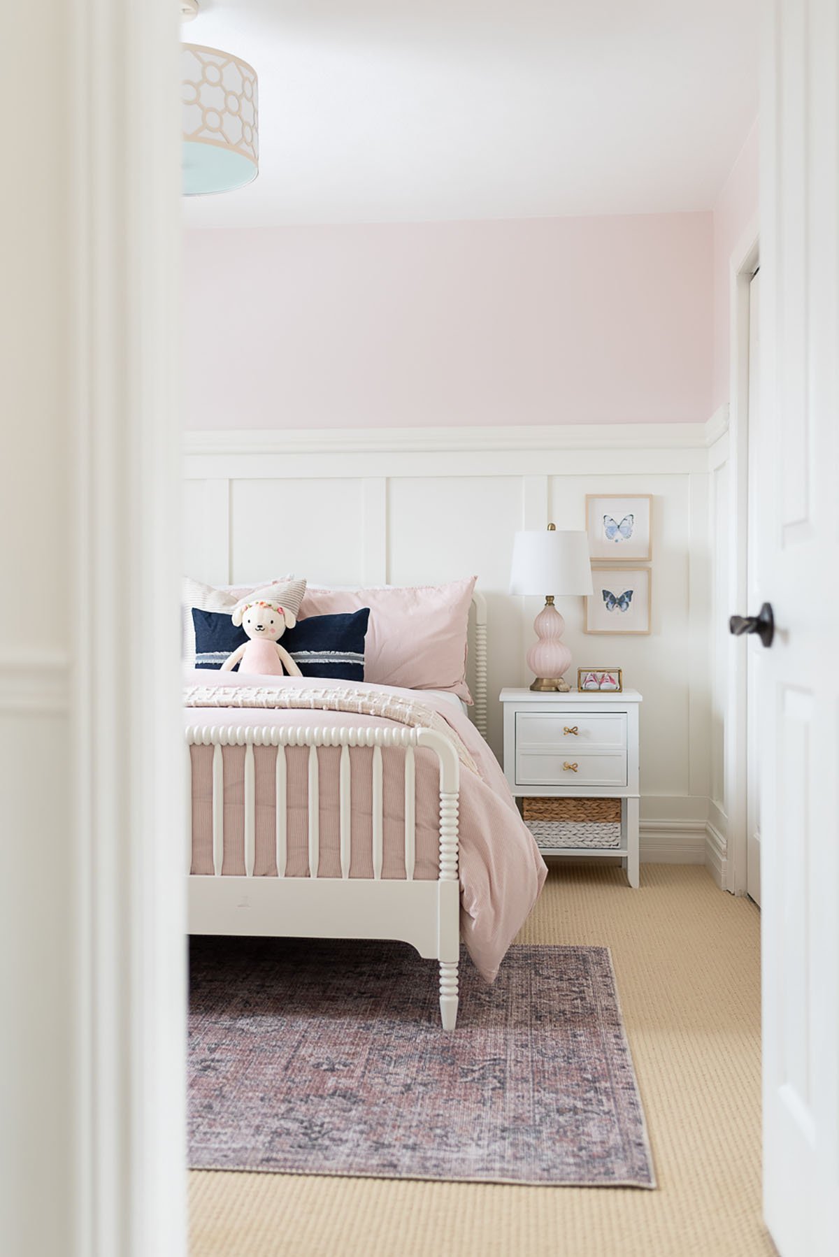 Little girl's bedroom with white wainscoting, white furniture and upper half of walls painted Benjamin Moore Pink Bliss. 