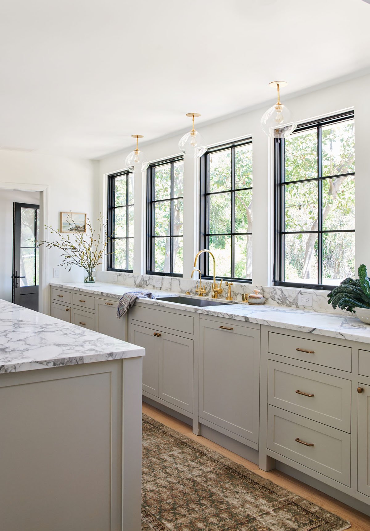 Dunn Edwards Shade kitchen cabinets with gold fixtures. Lots of natural light and marble counters.