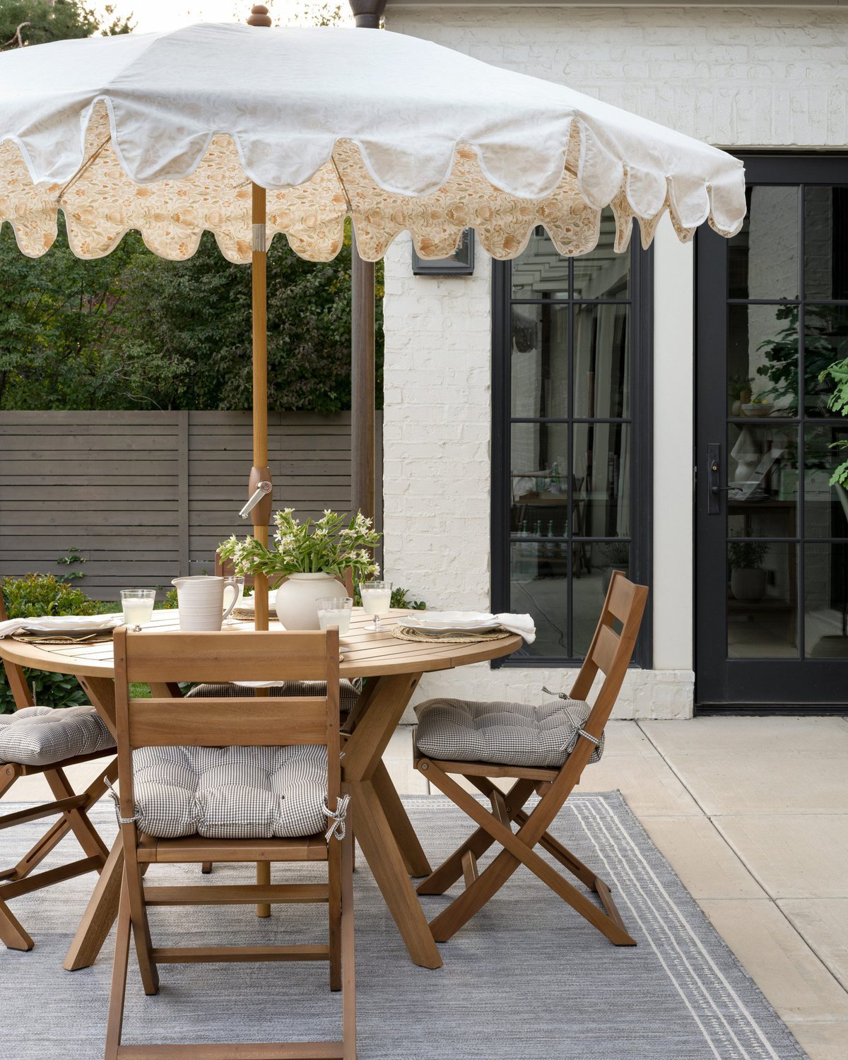 round wooden patio table with folding chairs and a patio umbrella.